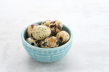 Fresh Quail Eggs served in bowl on grey background. Space for text
