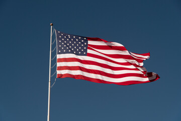 Flag of the USA is waving on blue sky background. National symbol of the United States of America, independence, patriotism, freedom, honor, democracy concept