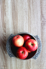 Silver bowl full of red apples on wooden table. Top view.