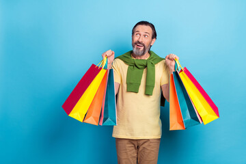 Photo of positive person hold packages look interested empty space isolated on blue color background