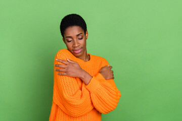 Photo of сute young brunette lady hug herself wear unisex jumper isolated on green color background