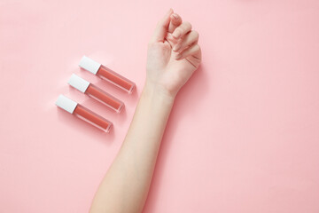 Top view of hand model holding lipstick in pink background for cosmetic advertising
