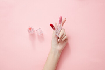 Top view of hand model holding lipstick in pink background for cosmetic advertising
