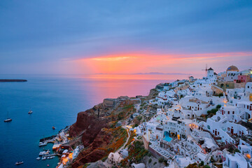 Fototapeta premium Famous greek iconic selfie spot tourist destination Oia village with traditional white houses and windmills in Santorini island on sunset in twilight, Greece