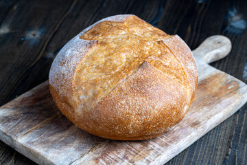 a whole loaf of bread on a cutting wooden board