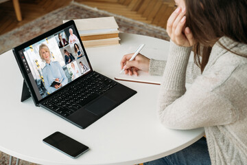 Business webinar. Home teleconference. Digital meeting. Cooperate team watching female coach video presentation online on laptop screen.