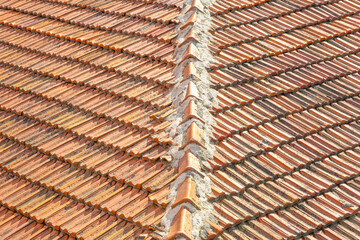 Weathered roof tile in orange color with corner of the roof, old and dirty tiles, wide angle