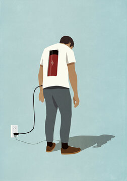 Man charging battery in back with plug, standing at electric outlet
