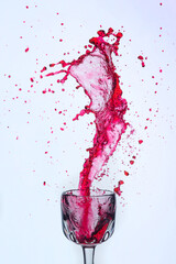 A splash of red wine in a glass on a white background.