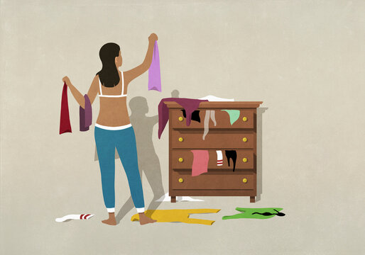 Woman getting dressed at messy bedroom dresser
