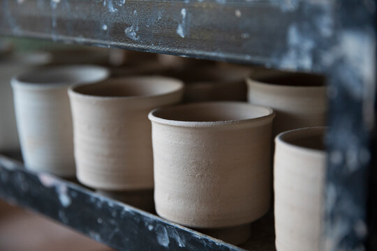 Close up thrown clay cups drying in a row
