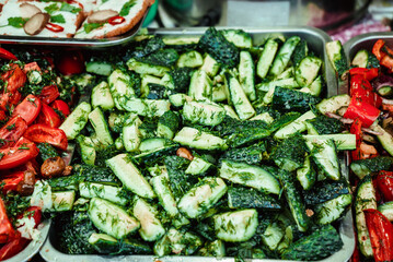 fresh fragrant cucumbers, onions and tomatoes with dill, herbs and spices lie at the food fair on the food court 1