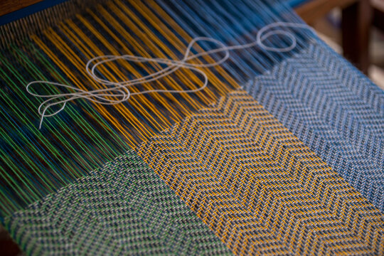 Blue, green and orange thread on loom

