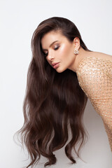 Beautiful elegant brunette female model with long shiny hair and golden earring portrait