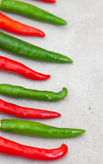 bright small red and green chilies on light grey with copy space