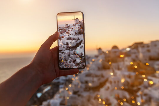 Tourist taking photo of the famous Santorini view using mobile phone camera. Vacation in Greece.