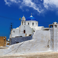 Fototapeta premium White church with a blue dome on Santorini island in Greece. Hot summer sun day.