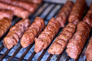 Preparing meat rolls called mici or mititei on barbecue. close up of grill with burning fire with flame and smoke.