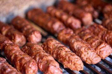 Preparing meat rolls called mici or mititei on barbecue. close up of grill with burning fire with flame and smoke.