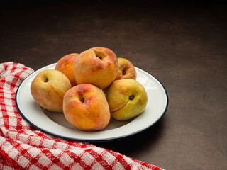 Group of fresh ripe peaches fruit on a white dish and cloth over the vintage background