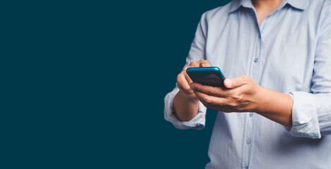 Close-up of hands using a mobile phone while standing over a blue background