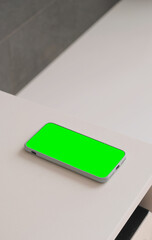 Mockup of the phone with chroma key green screen on the table.