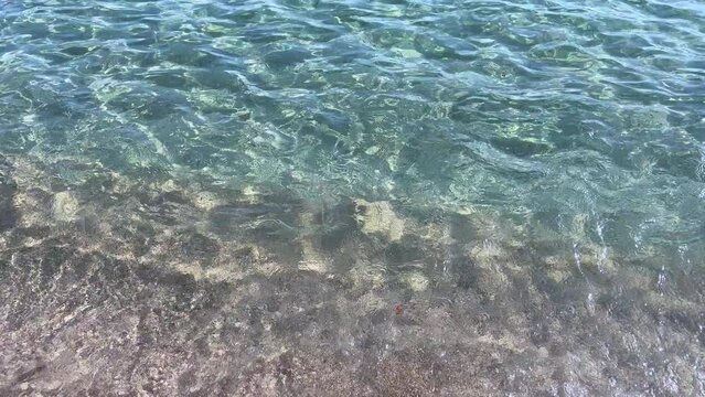 Close up shot of a beautiful crystal sea near the shore, with little waves and the sound of the sea. Relaxing, peaceful, mediterranean summer mood. Ibiza Cala Conta beach. 