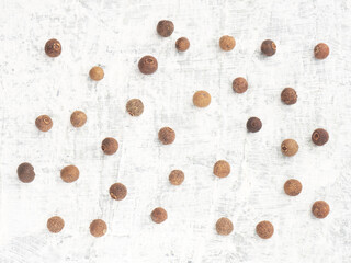 Small bunch of spice Allspice (Jamaica pepper, Pimento) on white concrete background. Macro. Flat lay. Indian cuisine concept
