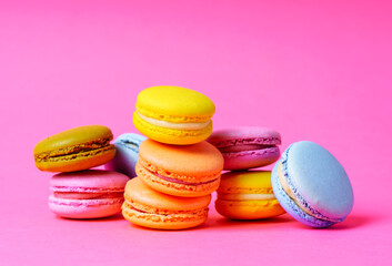 Colorful french macarons on a pink background.