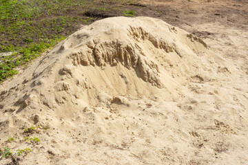 Half of a pile of sand on the ground and grass