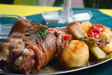 Serbian pork knuckle (svinjska kolenica) stewed under sać pot with potatoes and vegetables