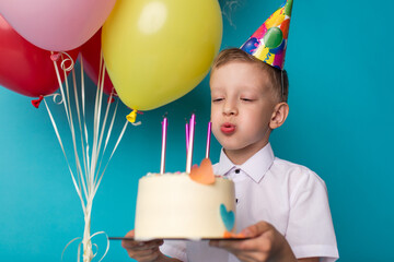 Little cute boy blowing candles on cake, happy birthday party