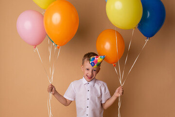 Cheerful little boy with balloons on the beige background