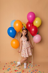 Fototapeta na wymiar Happy Birthday party. Child girl with balloons on beige background