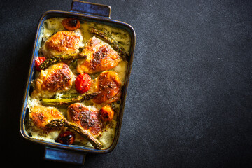 Baked chicken thighs with asparagus and vegetables in a creamy sauce.