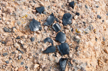 Broken black plastic pieces on abstract pebble stones gravel texture background