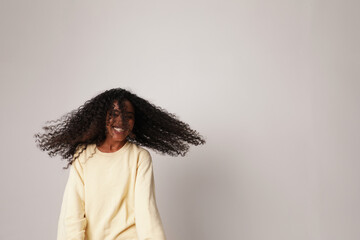 Happy African American young woman dancing on white background. Vertical.