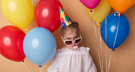 Happy Birthday party. Child girl with balloons on beige background