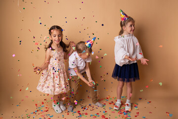 Happy birthday children girls and boy with confetti on beige background