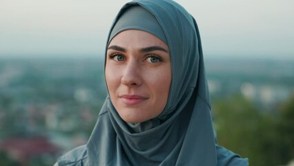 Close up Portrait of beautiful woman in hijab on top of the hill in the evening. Healthy life concept. City view horizon in background