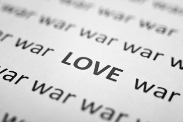 War and peace, picifist concept. Close-up of printed text of words War and one word Love on white paper. Low angle view, selective focus, macro photo