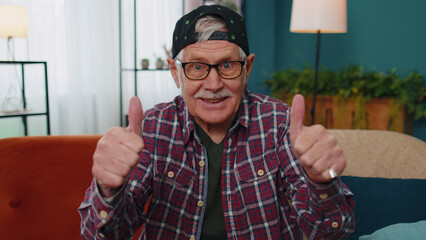 Caucasian senior grandfather looking at camera with toothy smile, raises thumbs up agrees with...