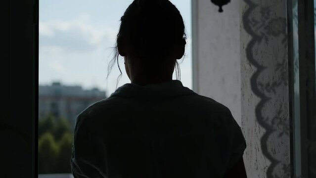 Young woman goes to balcony and look at the city