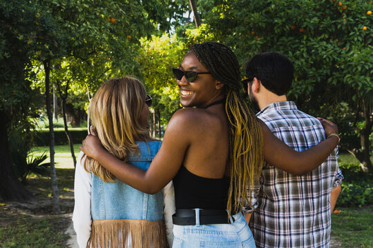 Multiracial group of friends walking in a natural park. Polyamorous relationship.