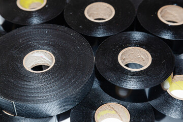 Several skeins of black electrical tape stacked next to each other, close-up.