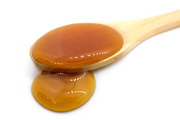 Date syrup and wood spoon on white background - close-up