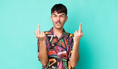 young adult hispanic man feeling provocative, aggressive and obscene, flipping the middle finger,...