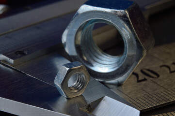 Accurate measuring tool caliper and metal ruler lie in place with nuts. close-up.