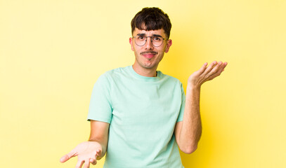 young adult hispanic man looking puzzled, confused and stressed, wondering between different...
