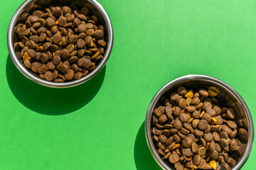 Two pet bowls with kibble on the green background